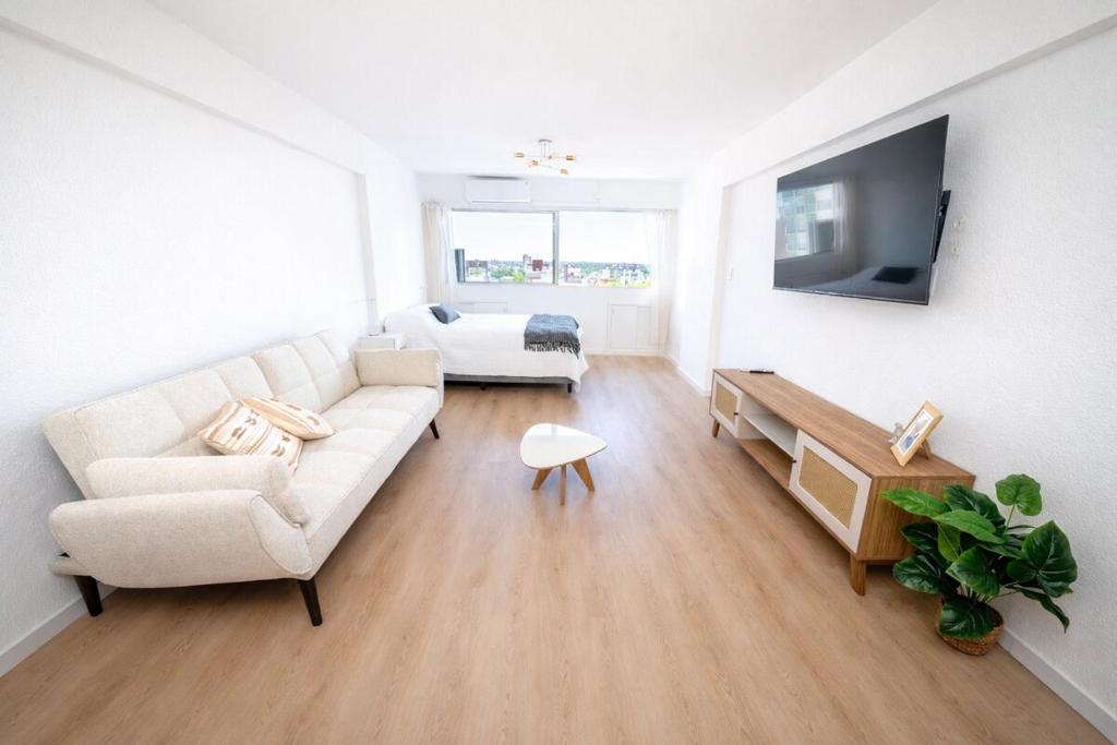 a living room with a white couch and a tv at Monoambiente amplio , moderno y super completo in Montevideo