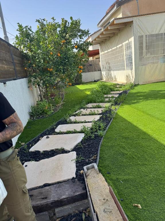 a person standing next to a yard with an orange tree at הבית של גיא בנאי in Beer Sheva