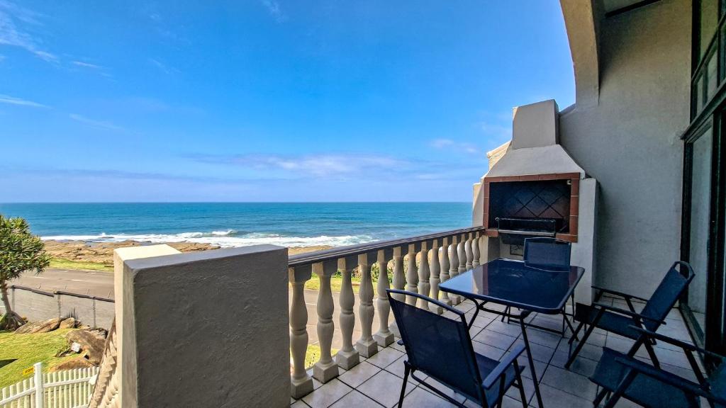 a balcony with a table and chairs and the ocean at Uvongo Cabanas 13B in Uvongo Beach