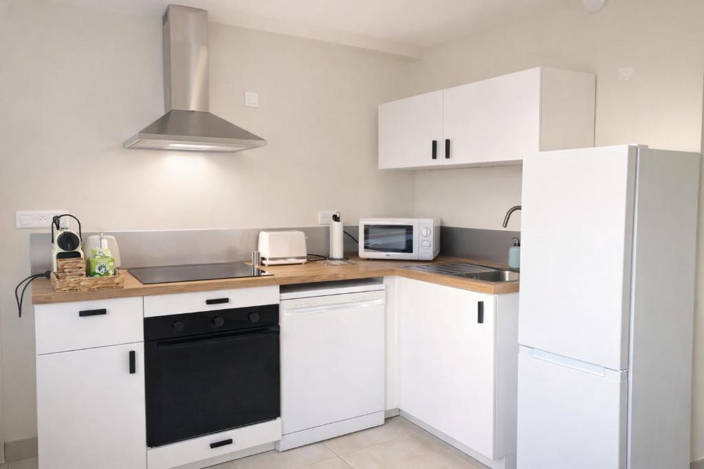 a kitchen with white cabinets and a black dishwasher at Les hébergements Rousseau in Oyonnax