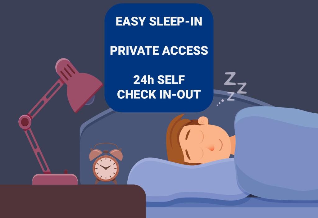 a man sleeping in bed next to an alarm clock at PRIVATE B&B - EASY ACCESS - 24h SELF CHECK IN-OUT in Odense