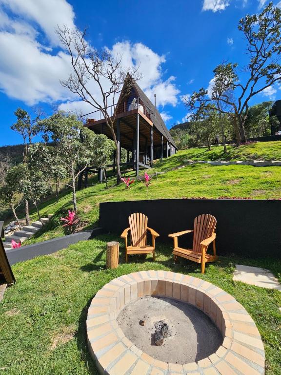 two chairs and a fire pit in front of a house at Recanto do Guará Cabana in Capitólio