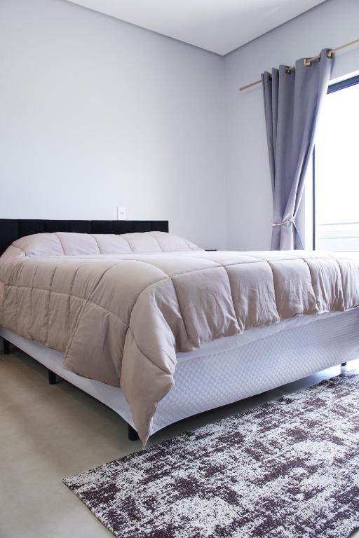 a white bedroom with a large bed with a window at Flat2 Aconchegante com Cozinha Completa in Sinop
