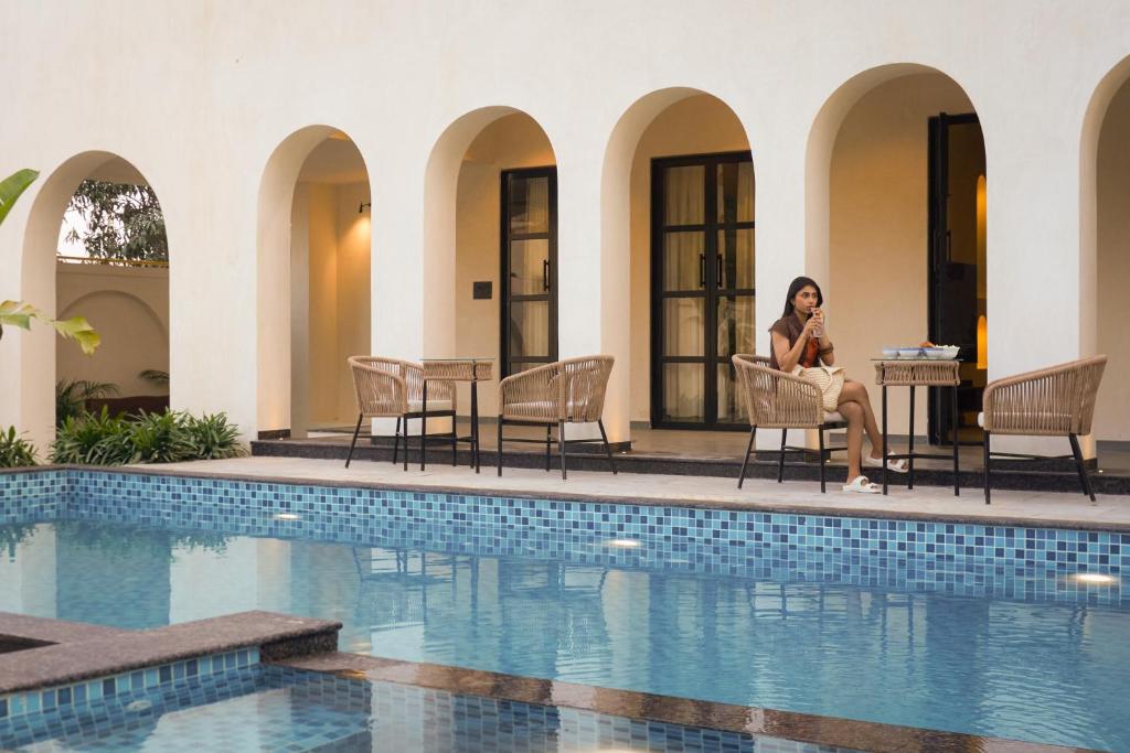 a woman sitting in a chair next to a swimming pool at Niwasa - A Luxury Boutique Stay, Udaipur in Udaipur