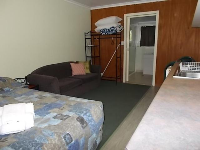 a room with a bed and a couch and a sink at Oakridge Motel Tourist Park in Oakey