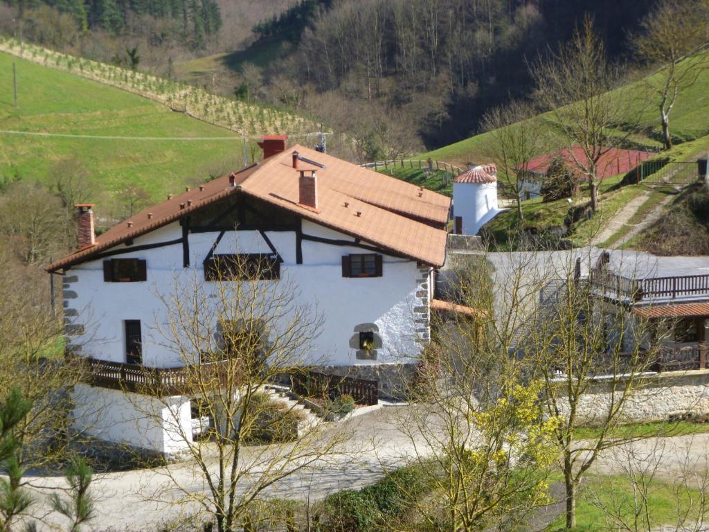 una casa blanca con techo rojo en una colina en Casa Rural Lazkaoetxe, en Zaldibia