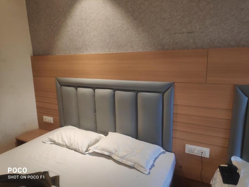 a bed with white pillows and a wooden headboard at Hotel Dreamland in Malsiān Shāhkot