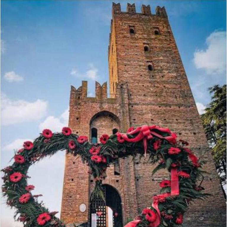 a large brick tower with a wreath on it at Residenza Il Castello Tre in CastellʼArquato