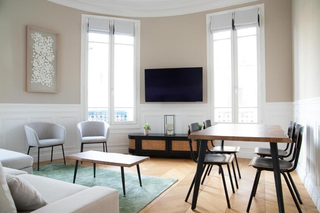 a living room with a table and chairs and a tv at Au bonheur de Troyes in Troyes