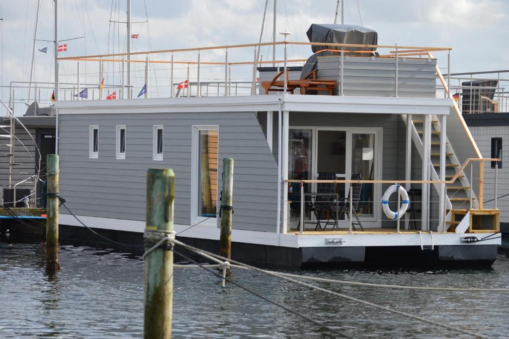 a small boat docked at a dock in the water at Hausboot Hecht mit Dachterrasse in Schleswig in Schleswig