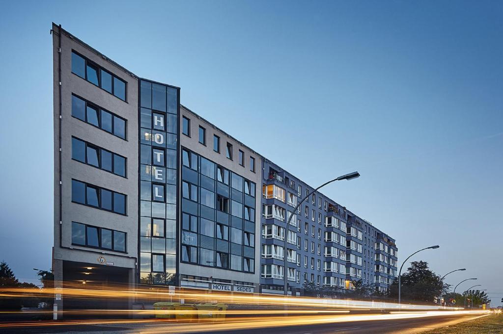 Un edificio alto in una strada cittadina con traffico di Hotel Sedes a Berlino