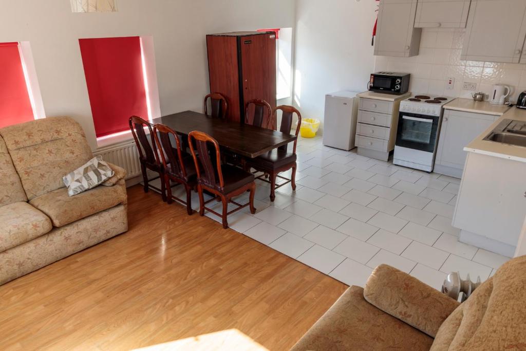 a living room with a table and a couch and a kitchen at Hacketts Bar And Accommodation in Kilkenny