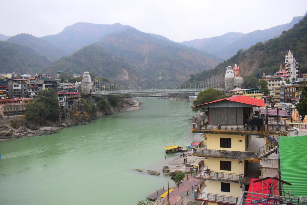 a view of a river with a bridge and buildings at Hotel V N Ganga in Rishīkesh
