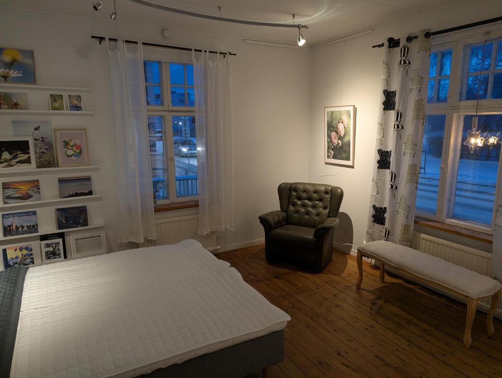 a bedroom with a bed and a chair and windows at Björk City - Charmig lägenhet nära centrum in Pietarsaari