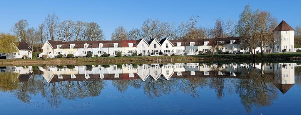 a large building sitting next to a body of water at Lakescape in Cirencester