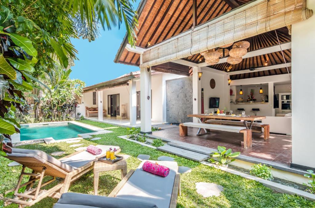 un patio al aire libre con piscina, mesa y sillas en Villa Can Barca, en Seminyak