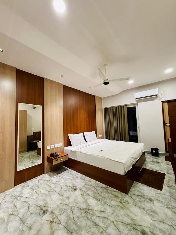 a bedroom with a large bed and a mirror at Neem Residency in Erāttupetta