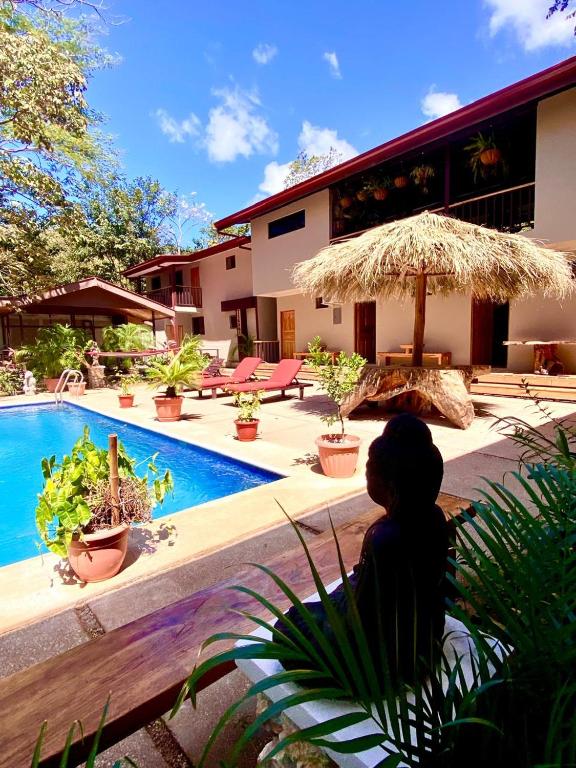a person sitting next to a swimming pool with an umbrella at Tekana Boutique Hotel Jungle Retreat in Tamarindo