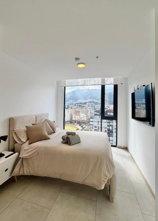 a white bedroom with a large bed and a large window at Cielo Apartments with top amenities in Quito
