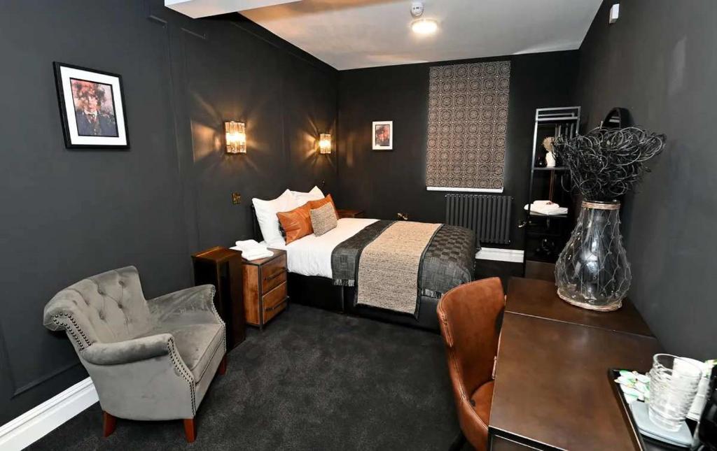 a bedroom with a bed and a chair and a table at The Royal Keep Hotel in Dudley in Dudley