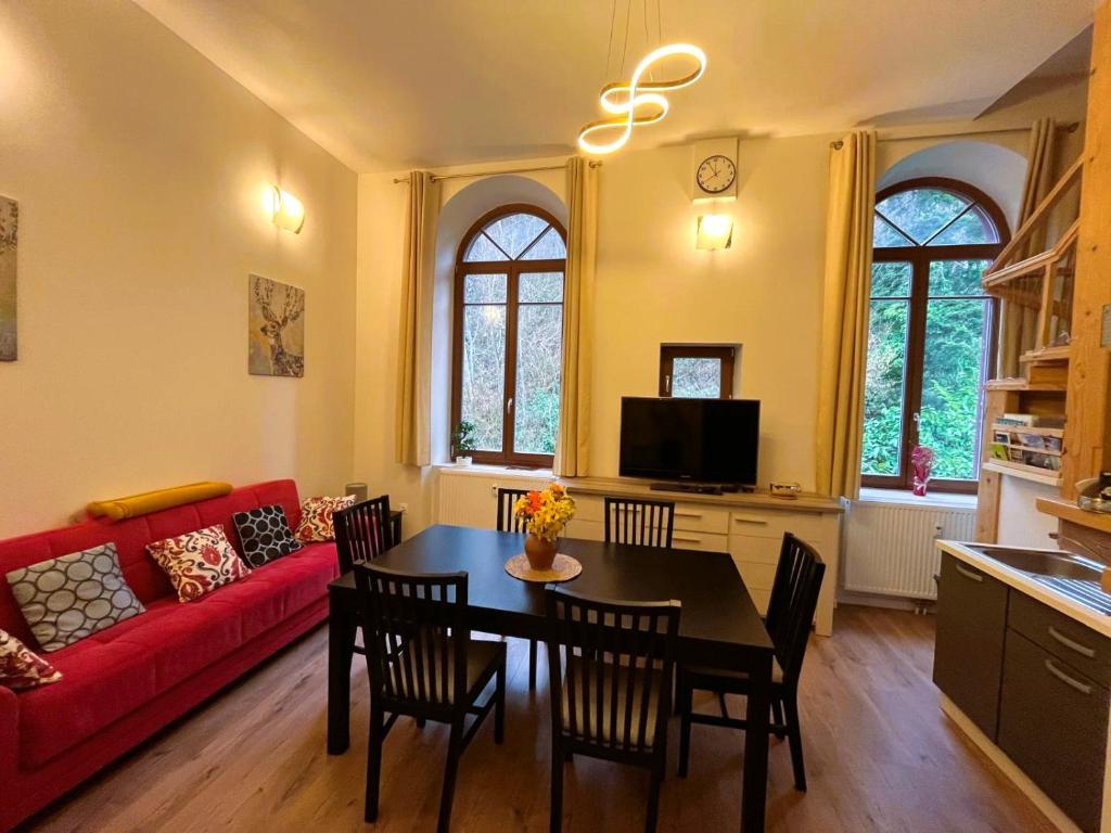 a living room with a table and a red couch at T4 en duplex, résidence atypique en pleine forêt in Yzeron