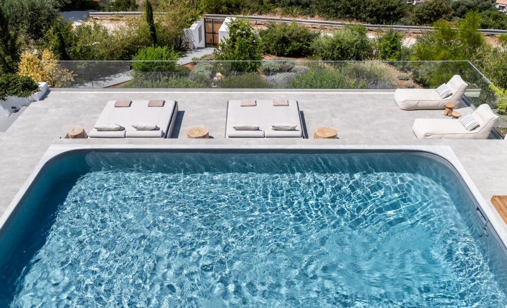 a swimming pool with two lounges and a swimming pool at Lourdas White Villa in Kefallonia