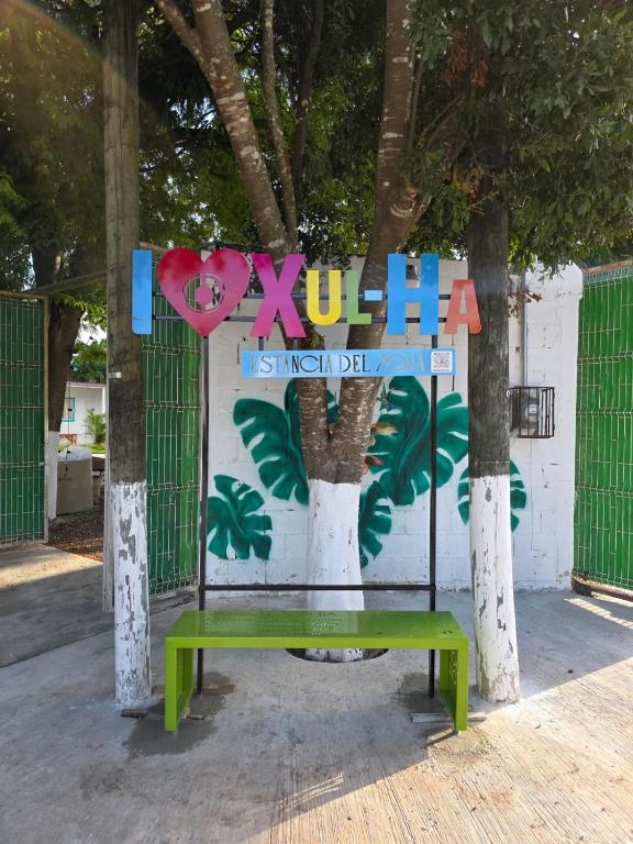 a bench in front of a sign with a tree at Hostal Estancia del Agua in Xul-Ha