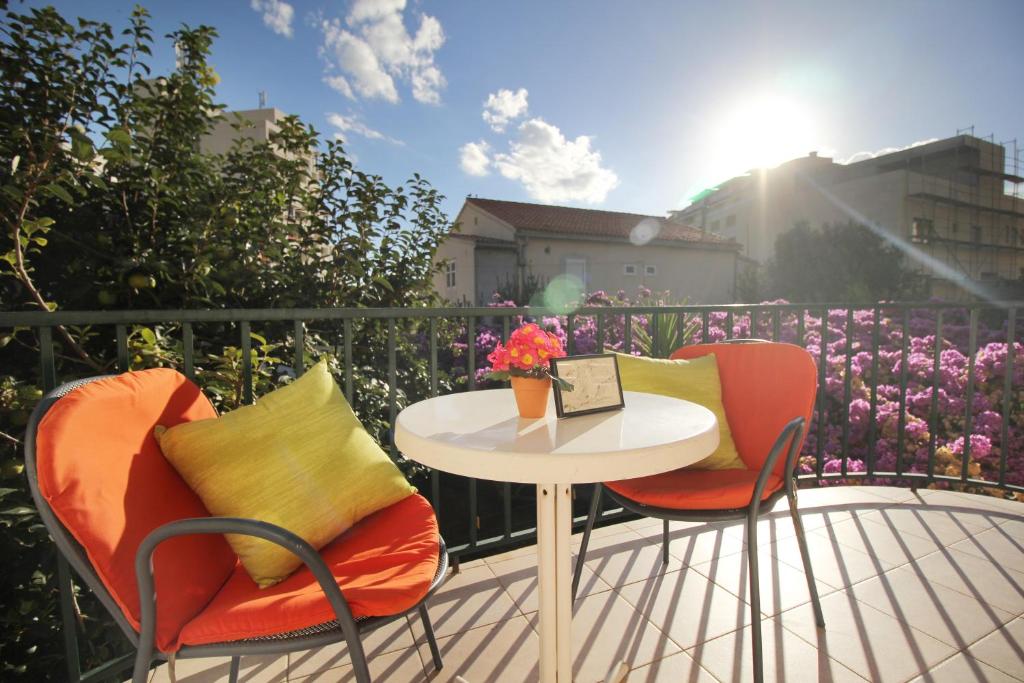 einen Tisch und zwei Stühle auf einem Balkon mit Blumen in der Unterkunft Apartments Nina Beach in Makarska