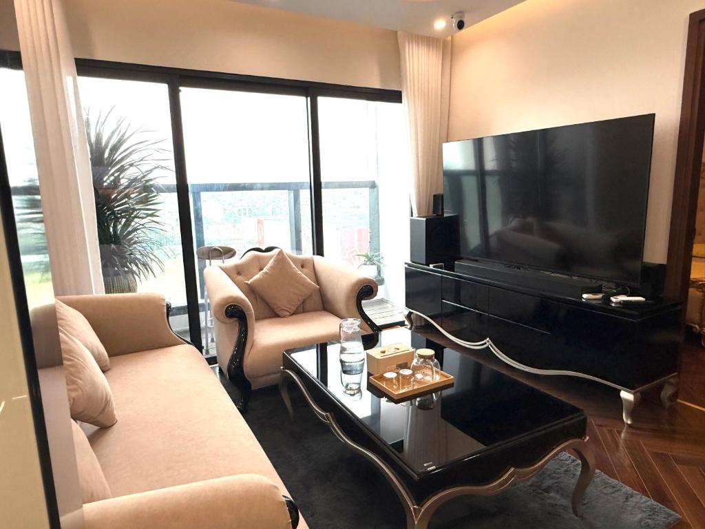 a living room with a tv and a couch and a piano at Hanaco Homestay in Hai Phong