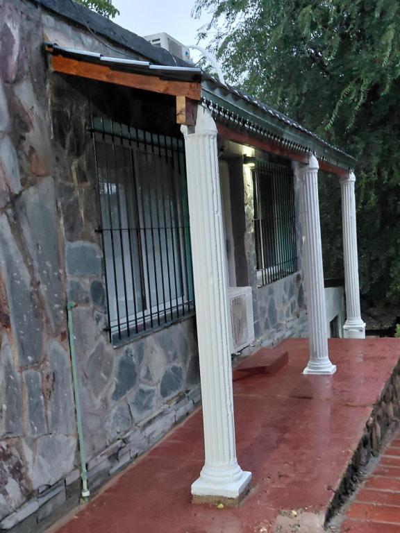 a porch with white columns on a stone building at La tranquera ll in Trapiche