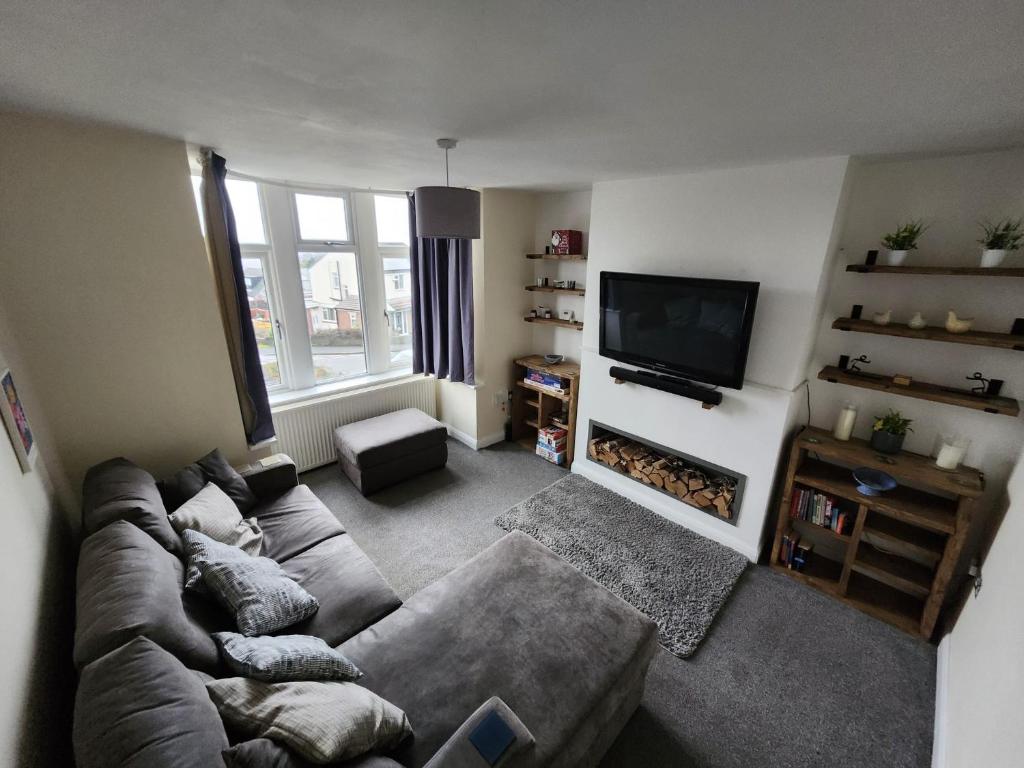 a living room with a couch and a flat screen tv at Bank End Cottage in Almondbury