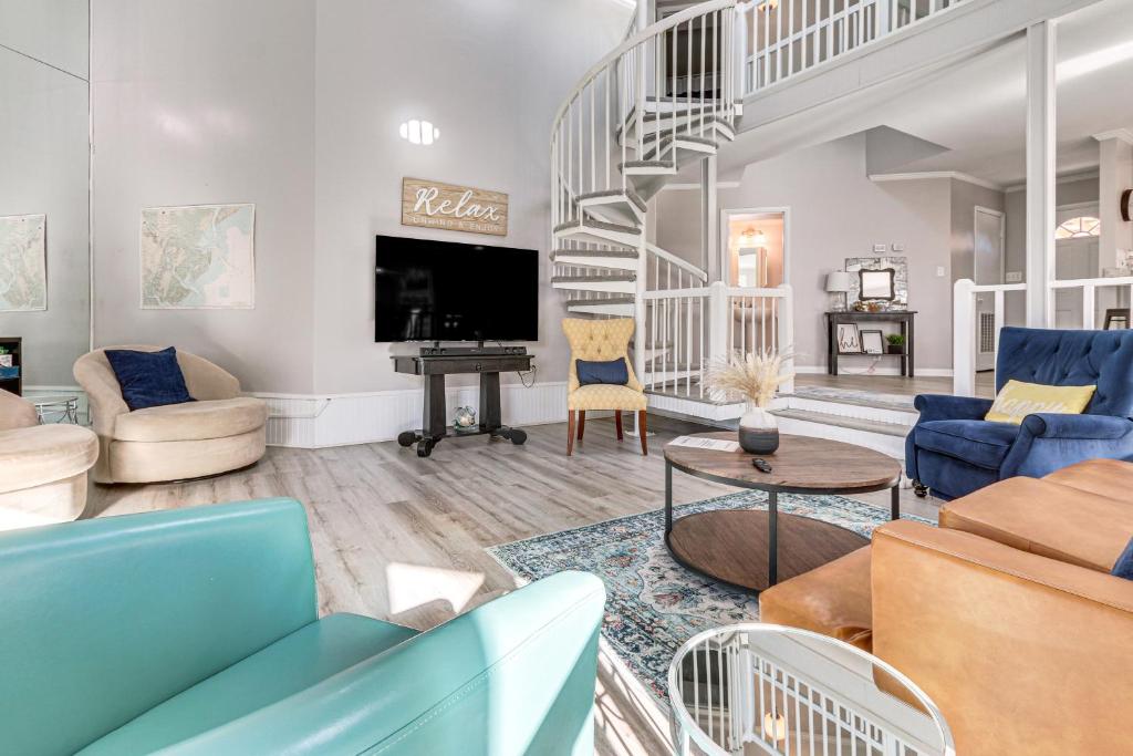 a living room with blue furniture and a staircase at Riverfront Savannah Getaway w/ Pool & Dock! in Savannah