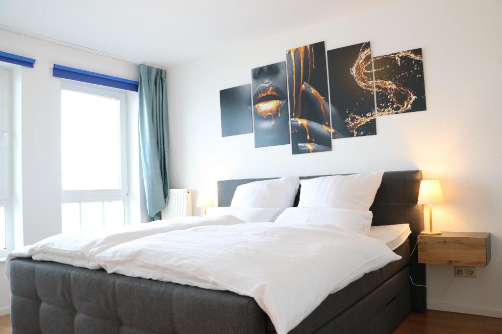 a bedroom with a large bed with four pictures on the wall at Suite im Zentrum Süd-Balkon Parken in Bad Lippspringe