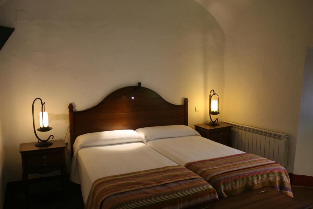 a bedroom with a large bed with two lamps at Hotel Rural Las Grullas in Villanueva del Fresno