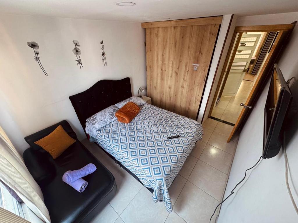 a small bedroom with a bed and a television at ApartaHotel Holguin in Estación El Salto