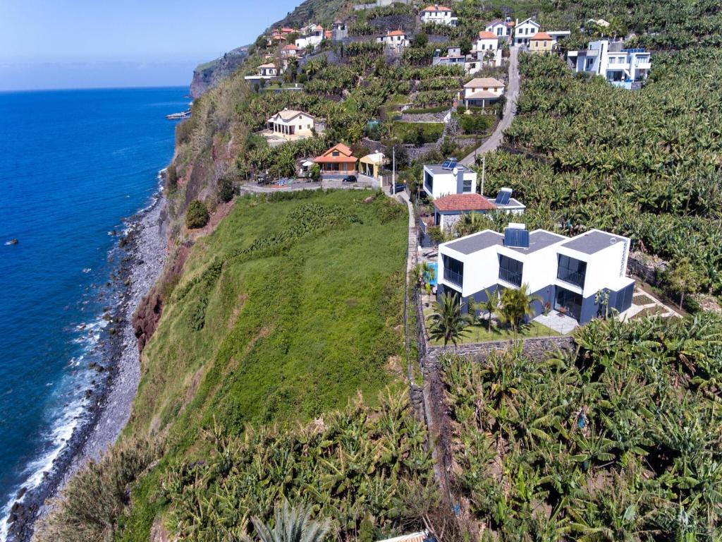 an aerial view of a house on a hill next to the ocean at Quinta Golfinho in Arco da Calheta