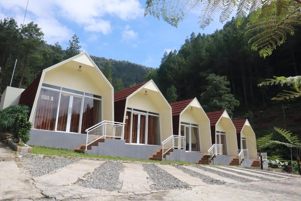 a row of cottages with trees in the background at Diiza Glamping Tawangmangu Private Pool No BBQ in Tawangmangu