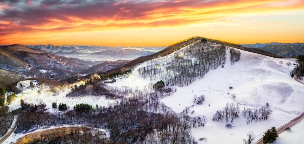 a mountain covered in snow with a sunset in the background at Mountain View Cottage by Carolina Mornings in Waynesville