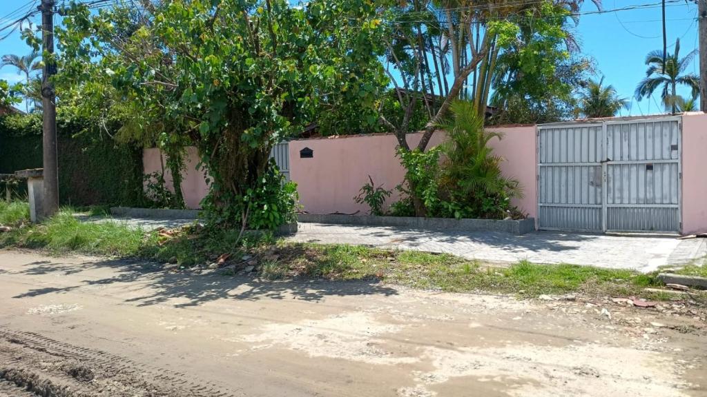 a house with a pink fence and a tree at Bruno Pereira in Guarujá