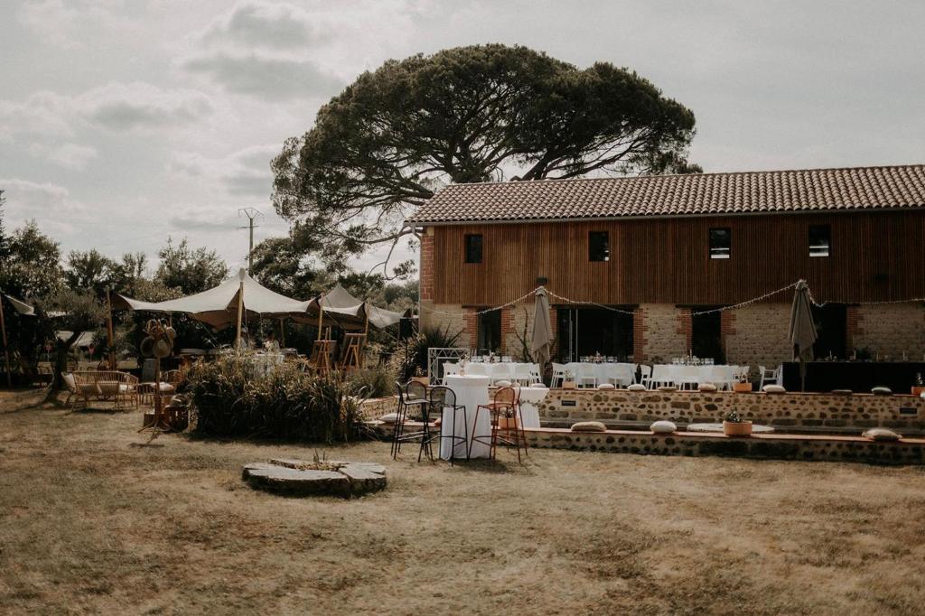 a barn with a building and a tree in the background at Domaine de Barthas in Castelnau-Magnoac
