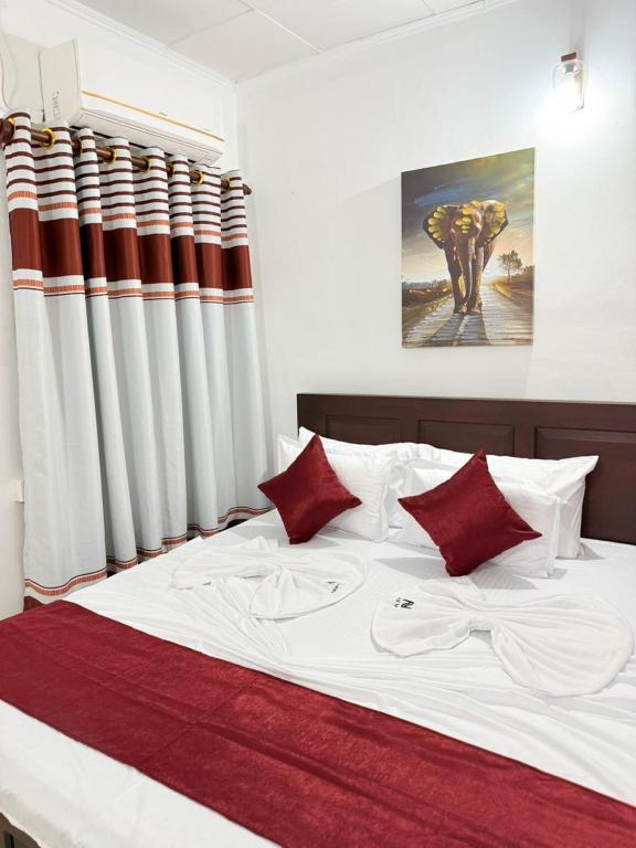 a bedroom with a large bed with red pillows at Nishi Villa in Negombo