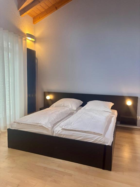 a bedroom with a large bed with white sheets and pillows at D&D Guesthouse in Angelbachtal