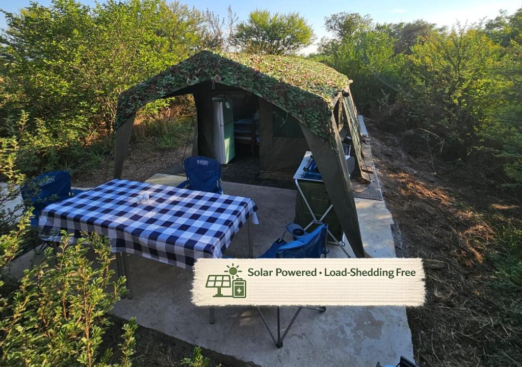 a gazebo with a table and chairs in front at Merry Mongoose Riverside Tent in Skeerpoort