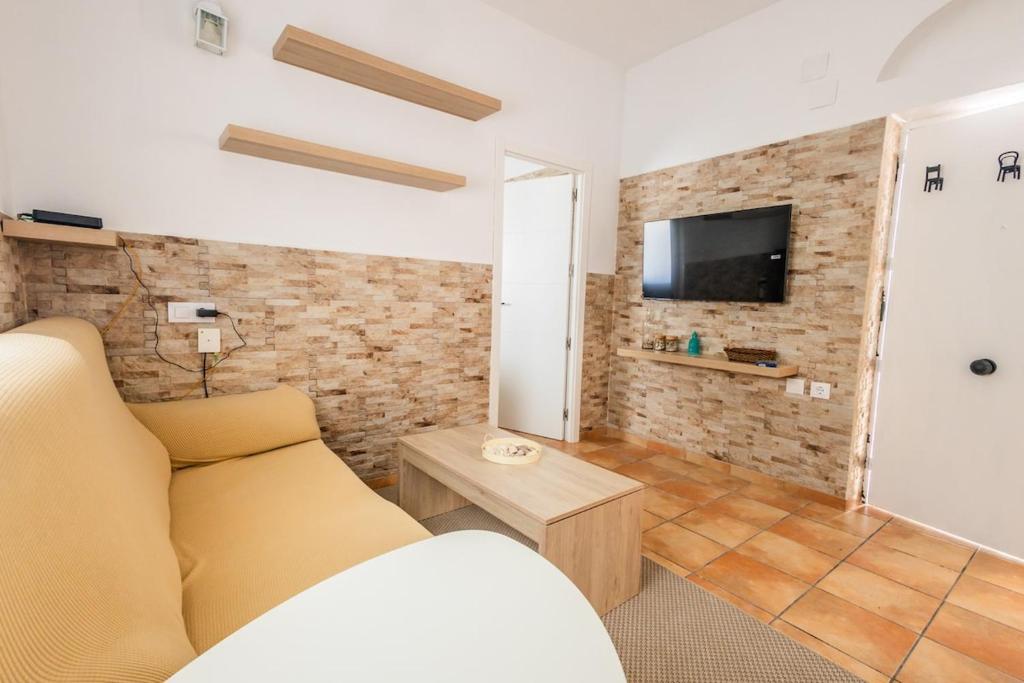 a living room with a couch and a tv on a brick wall at GuestReady - Calvario Rota 30 JC in Rota