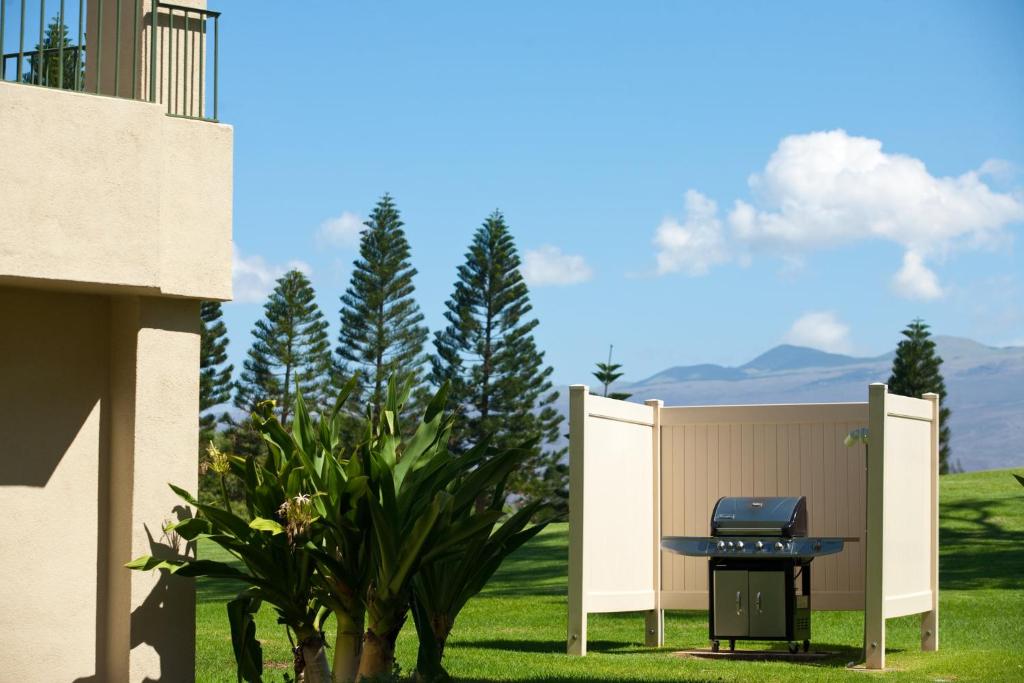 a barbecue grill in a yard next to a house at Paniolo Greens Resort in Waikoloa