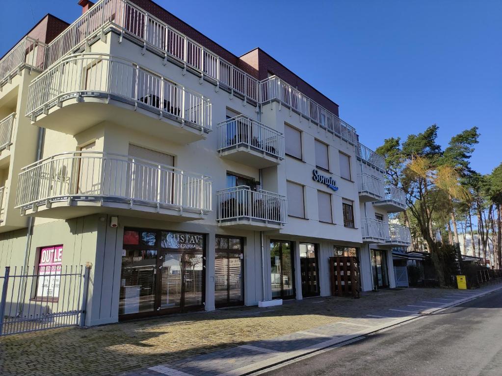 a white building with balconies on a street at Apartament Sonatka w Międzywodziu in Międzywodzie