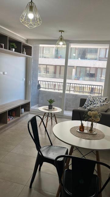 a living room with a table and chairs and a large window at Depa Céntrico con estacionamiento in Temuco