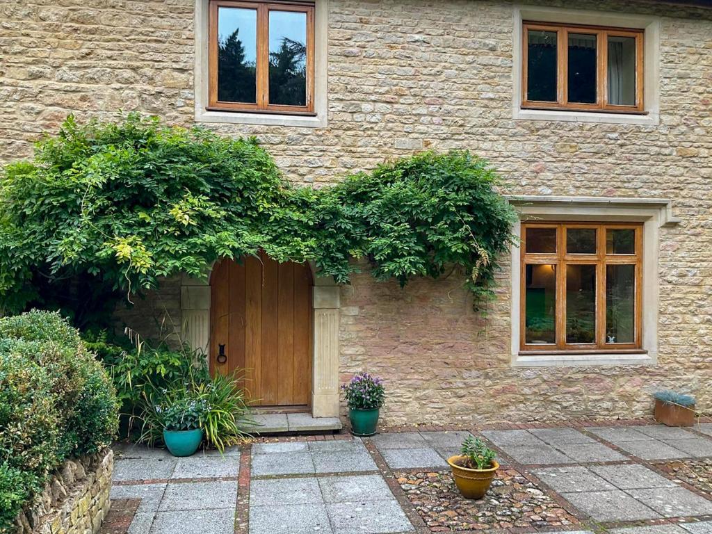 a brick house with a wooden door and plants at Church Barn in Olney