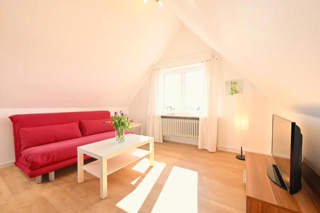 a living room with a red couch and a table at Dinkelbach Landhaus 1 B in Lindau-Bodolz