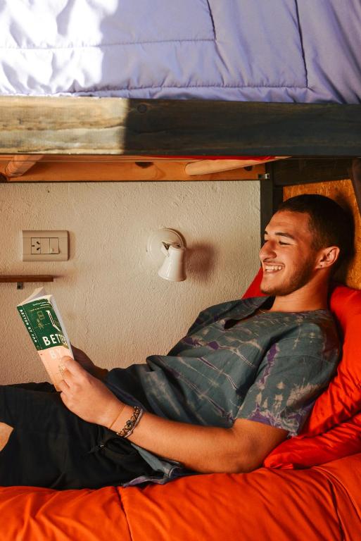 a man laying on a bed reading a book at Hostel Otto Tipp in El Bolsón